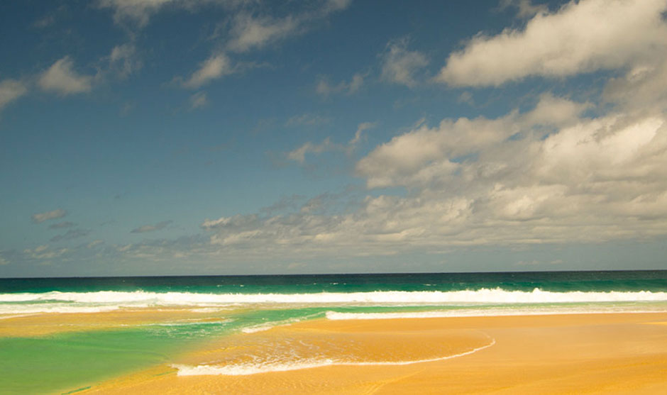 onde che si infrangono sulla spiaggia e cielo blu con effetto color bronzo