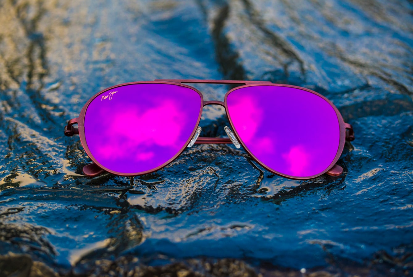 shallows style sunglasses with pink lenses displayed over wet rocks