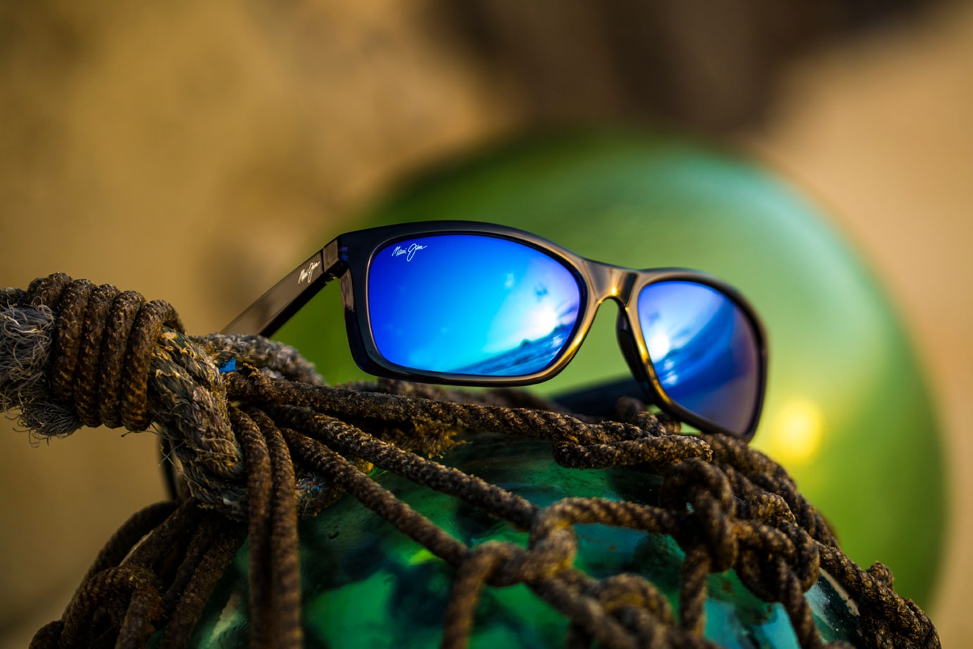 Puhi Sunglasses with Blue Lenses Resting on Rope