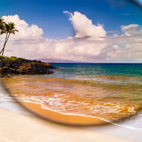 spiaggia mostrata attraverso la lente di un occhiale da sole color rosa
