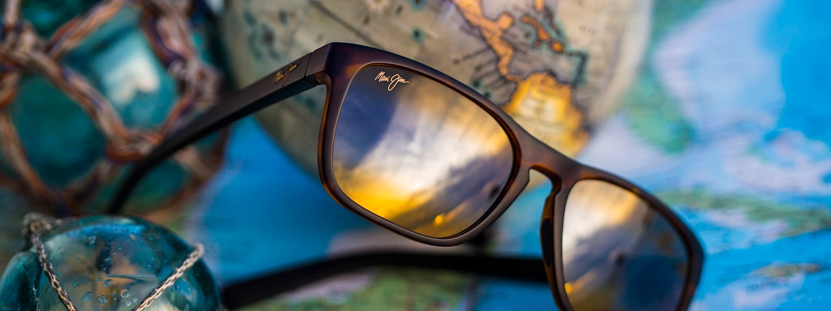 brown frame sunglasses with bronze lenses displayed over maps and globes