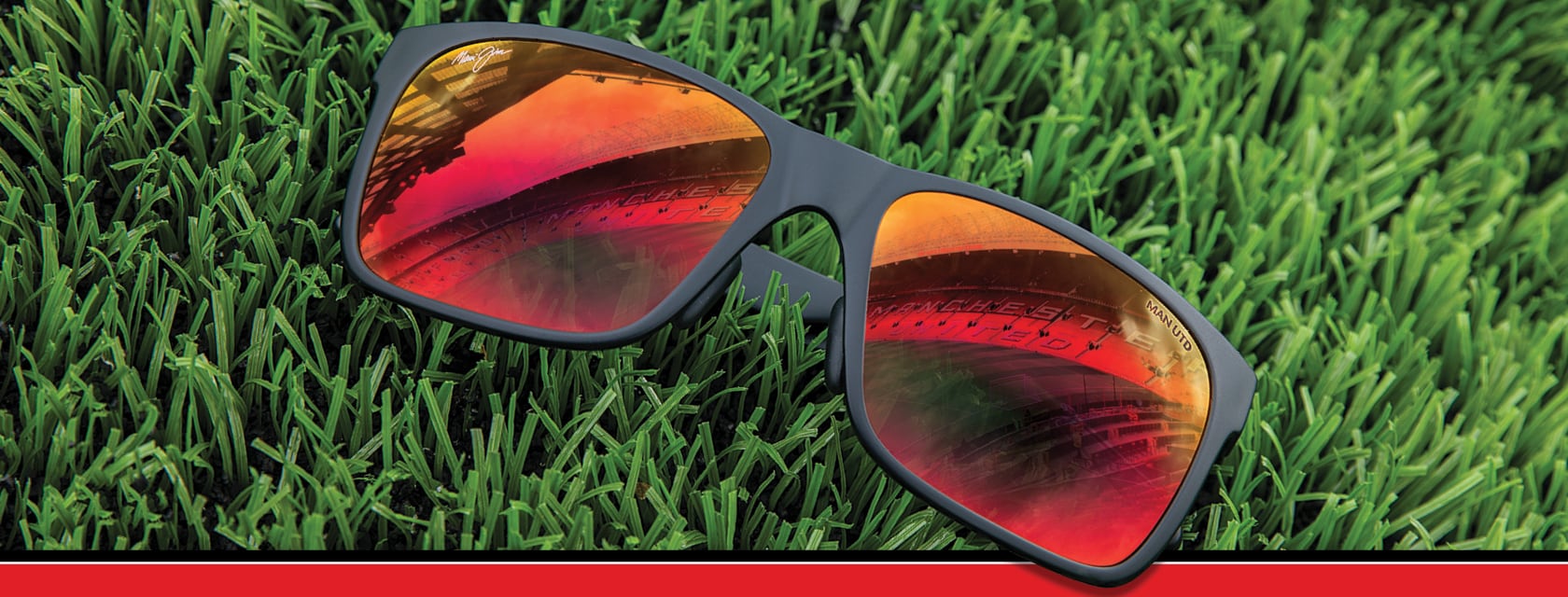 Red Sands sunglasses on grass, Manchester United stadium reflected from Hawaii Lava™ lens