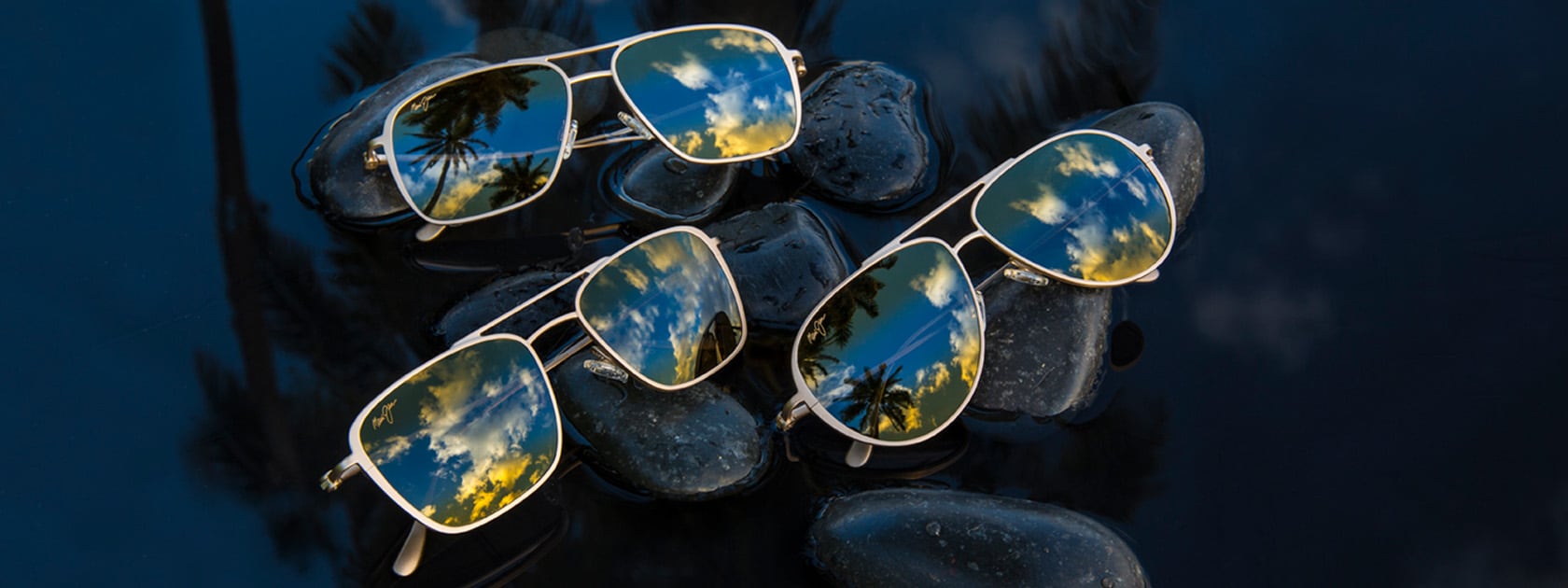 three different matte titanium sunglasses displayed on wet rocks