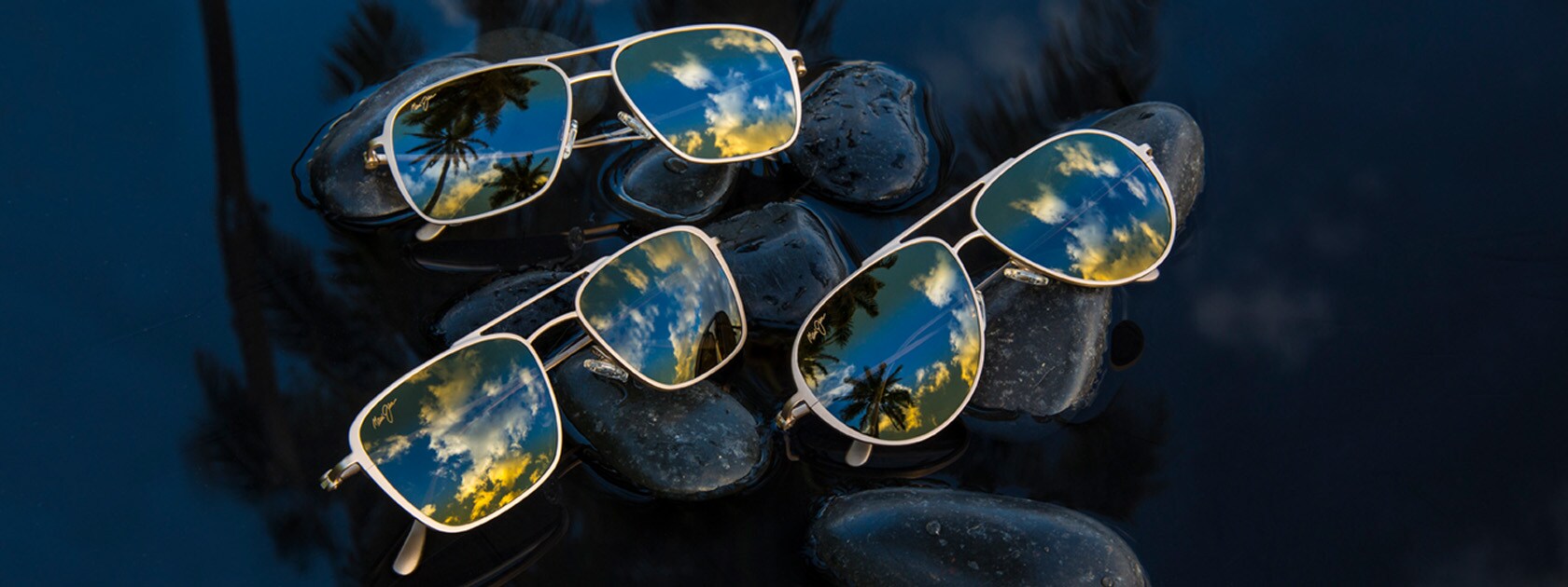 trois lunettes de soleil différentes en titane mates présentées sur des roches mouillées