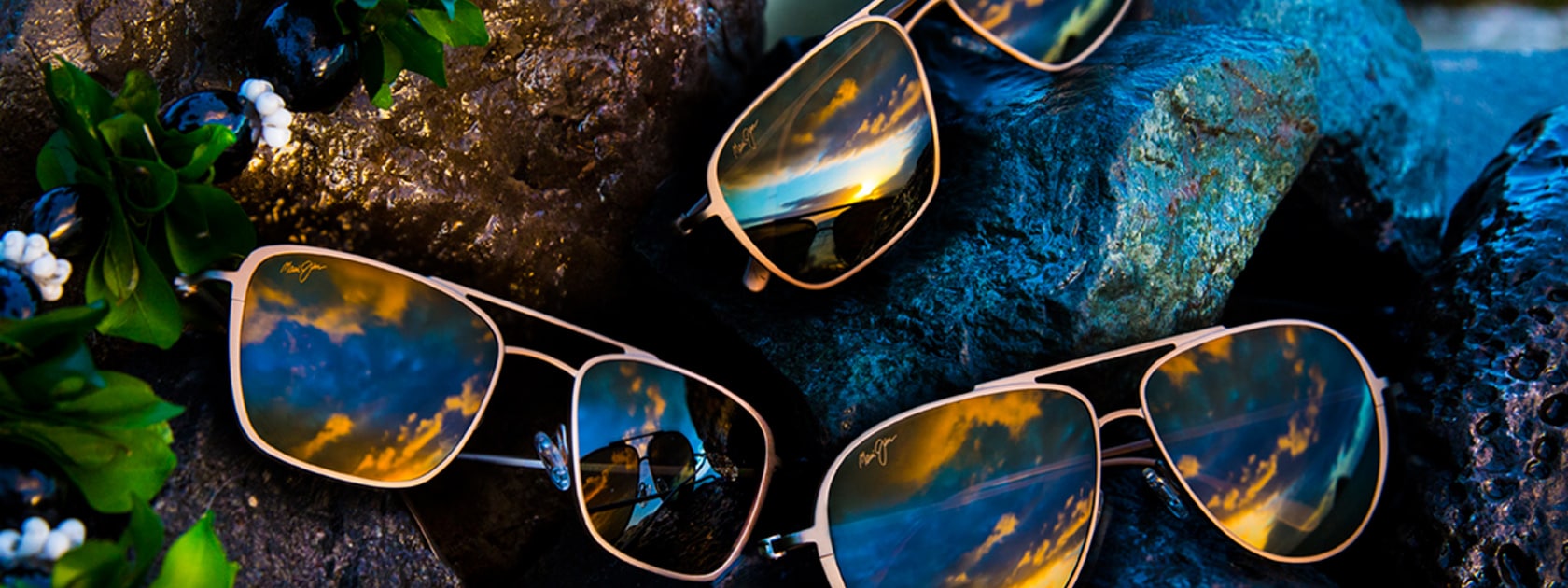 tres gafas de sol de titanio mate distintas expuestas sobre rocas mojadas
