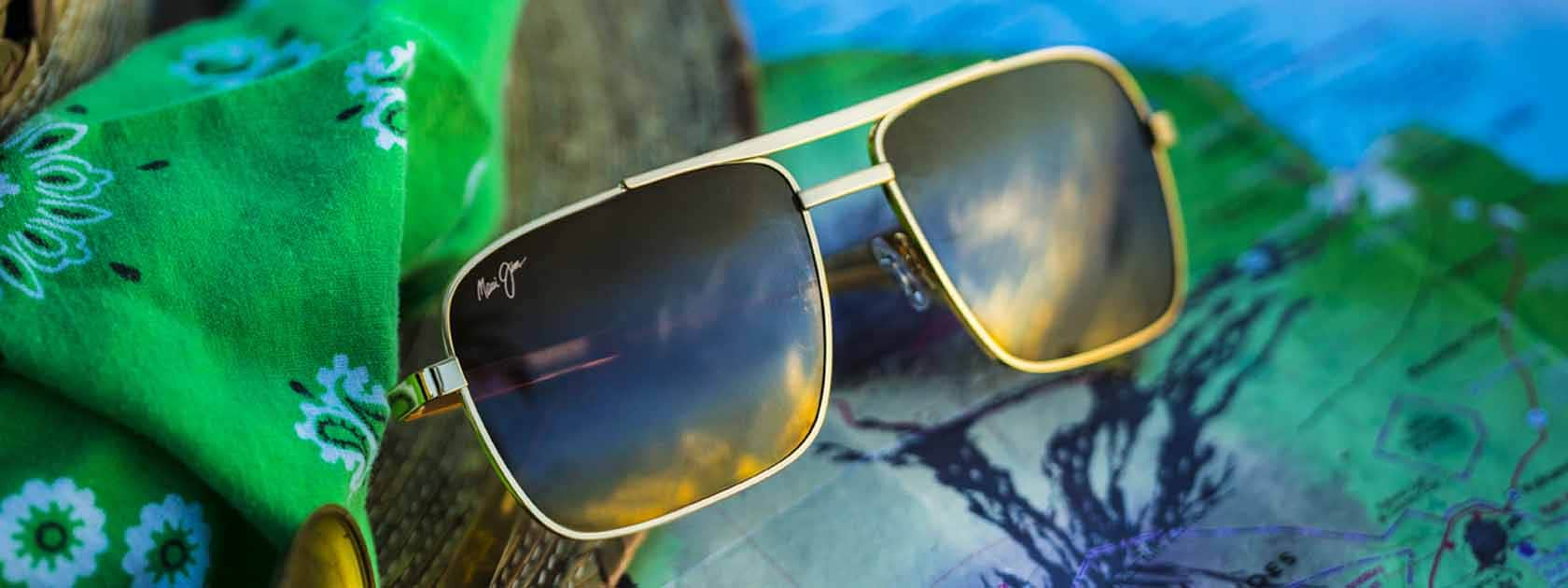 gold frame aviator sunglasses with bronze lenses displayed over green handkerchief