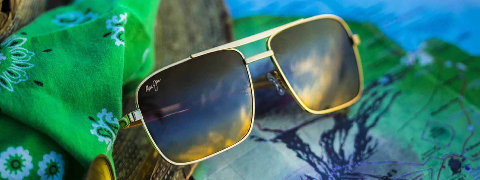 gafas de sol de aviador de montura dorada con lentes bronce expuestas sobre pañuelo verde