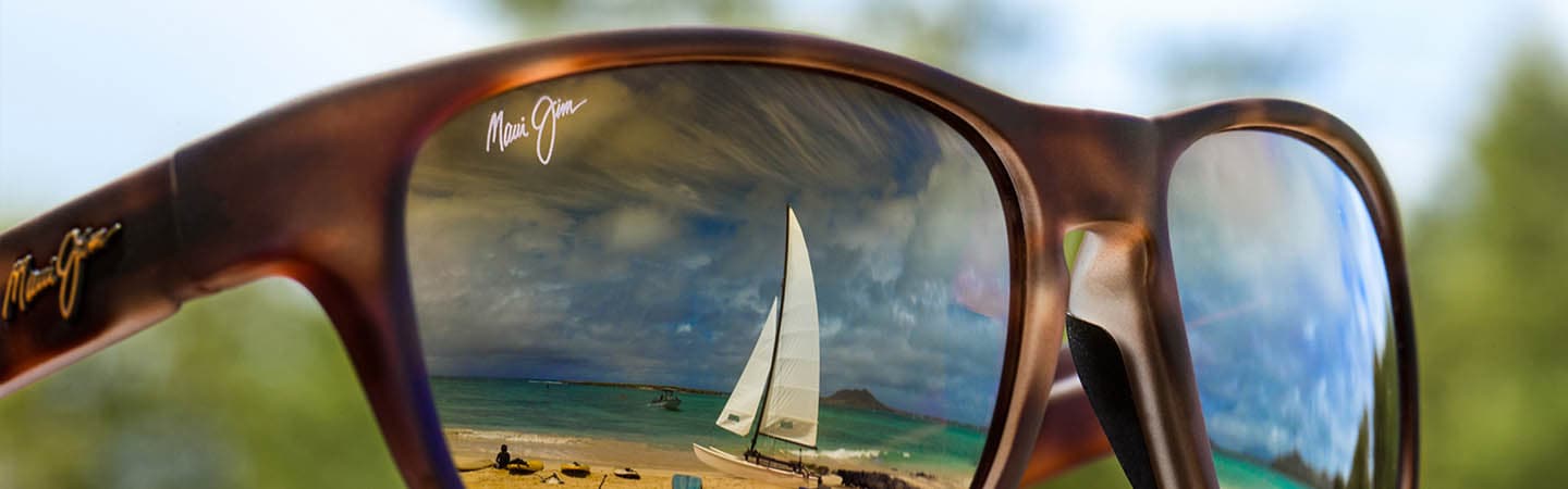 occhiali da sole con montatura tartaruga e riflessi di una barca a vela e cielo sulle lenti