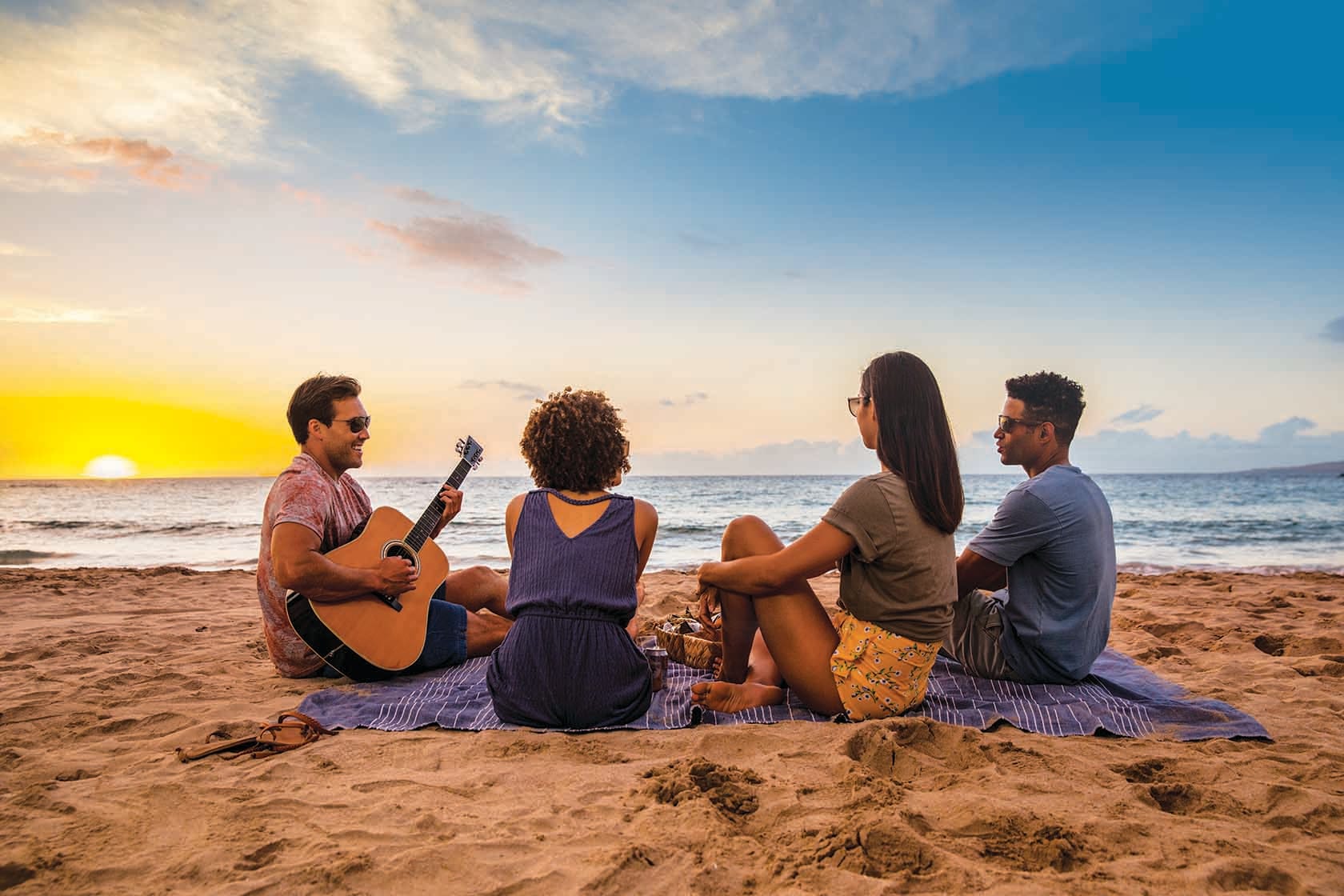 Cuatro personas en una playa con una guitarra