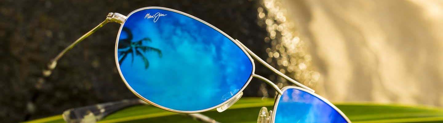 silver baby beach sunglasses with blue lenses on palm leaves