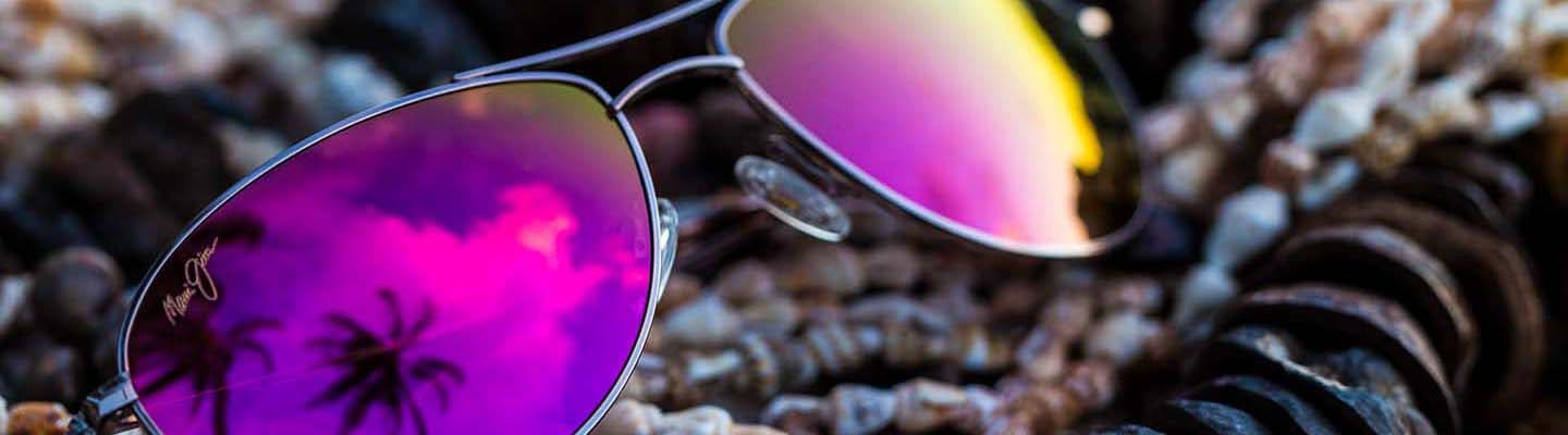 gafas de aviador de color rosa dorado con lentes rosas expuestas sobre conchas