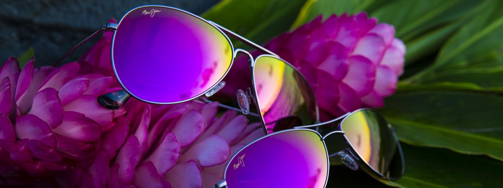 rose gold sunglasses with pink lenses displayed on pink tropical flowers