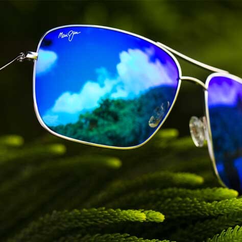 lentes de sol con armazón plateado con cristales azules que reflejan el cielo y palmeras