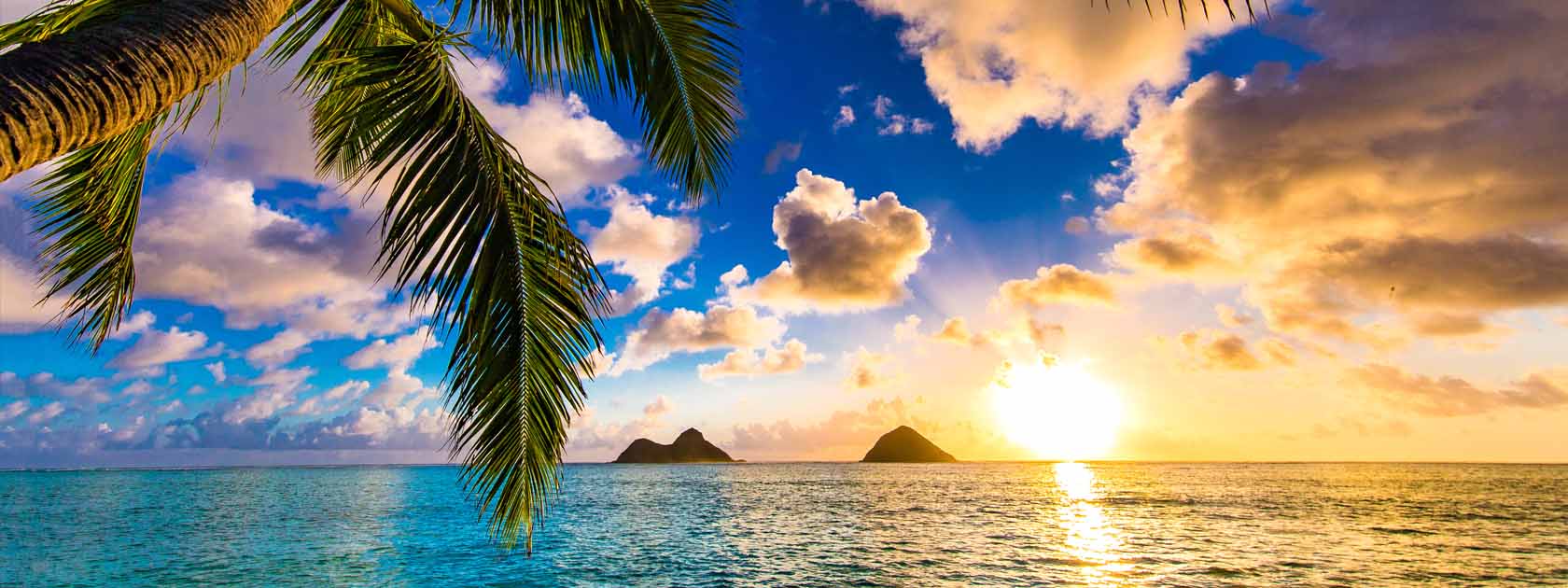 coucher de soleil au bord de l'océan avec palmiers et 2 petits îles au loin