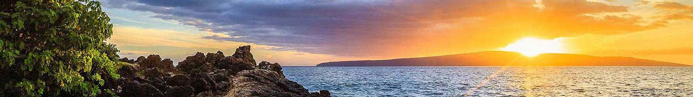 escena de puesta de sol en costa rocosa con océano y cielo