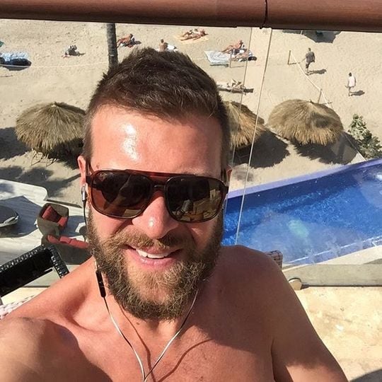 man wearing sunglasses and headphones taking selfie on balcony