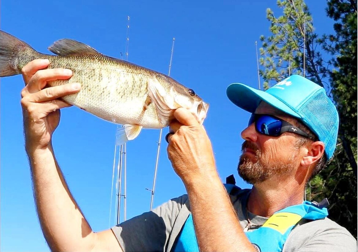 Man Wearing Blue Hawaii Local Kine Sunglasses, Holding a Fish and Looking into It's Mouth