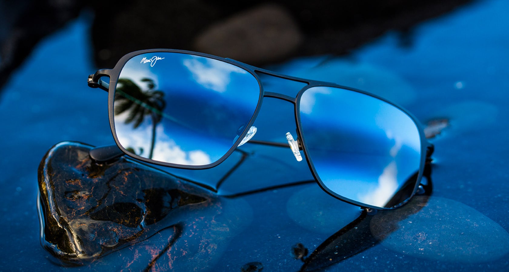 black matte titanium sunglasses displayed in water with rocks