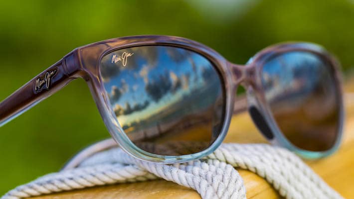 brown to blue faded sunglass frame with gray lenses displayed on rope wrapped wood post