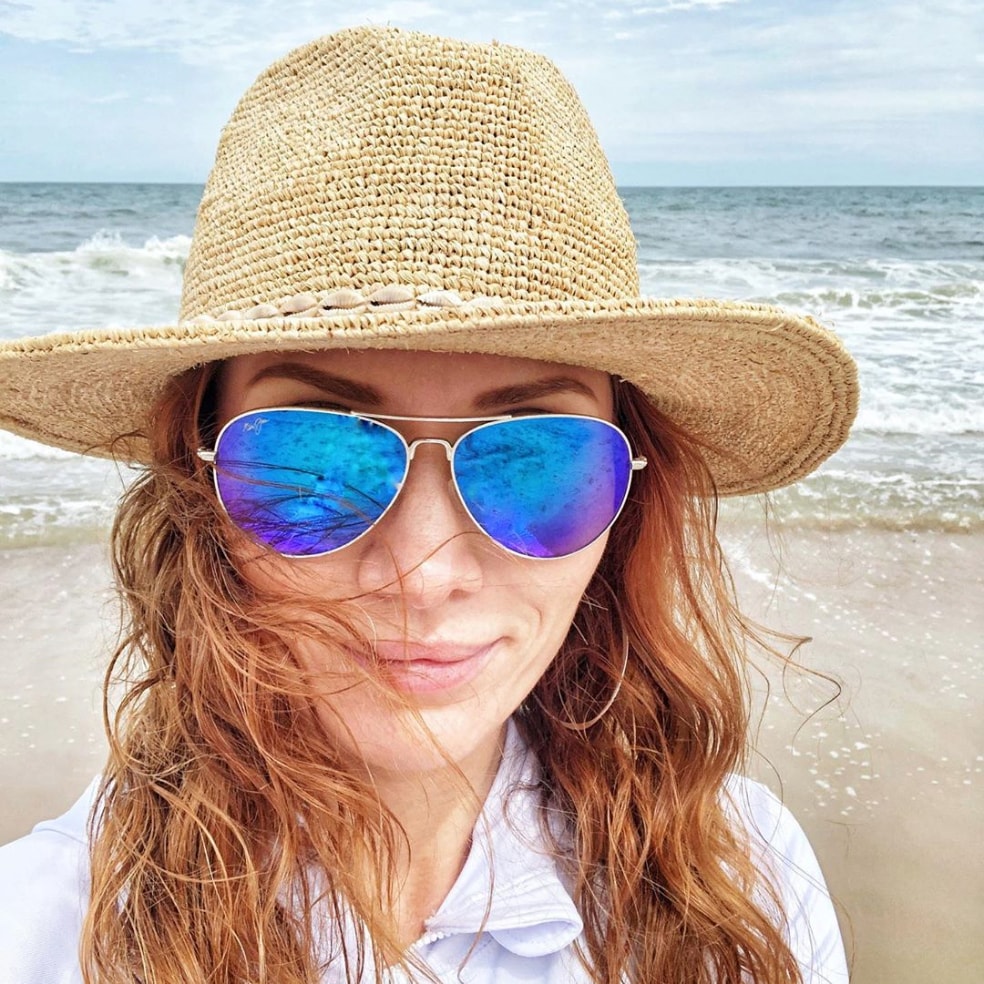 Chica en la playa vistiendo sombrero para el sol y Mavericks plateados con lente Blue Hawaii