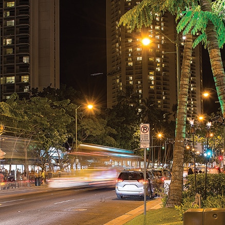 Zeitrafferbild einer tropischen Straße mit fahrenden Autos bei Nacht