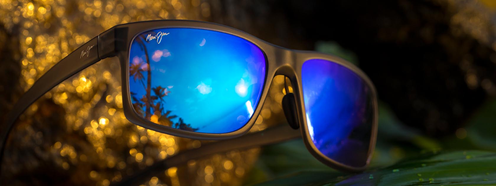 gafas de sol de color negro mate con lentes azules expuestas sobre superficie con textura amarilla