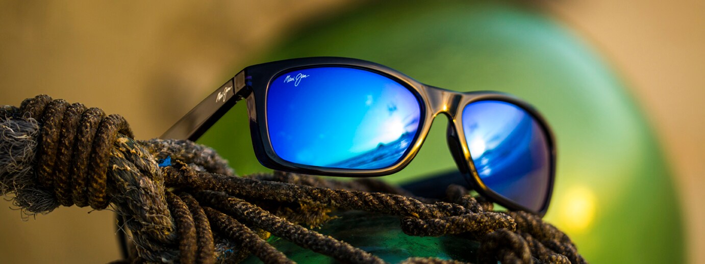 Puhi Sunglasses with Blue Lenses Resting on Rope