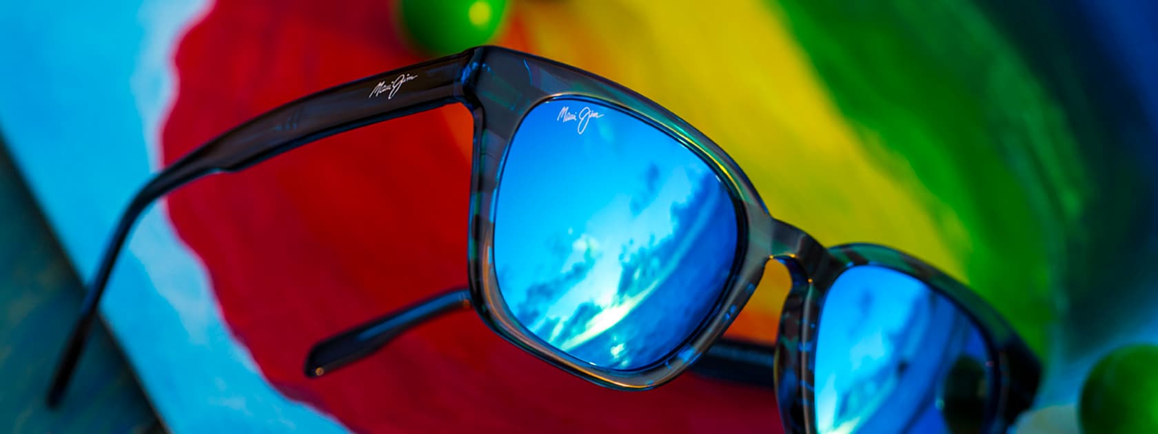 Sonnenbrille mit blauer Fassung und blauen Gläsern vor farbigem Hintergrund