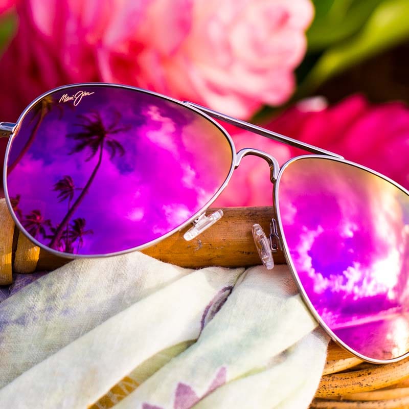 montura de aviador de color rosa dorado con lentes rosas expuesta en cesta con paño y flores rosas