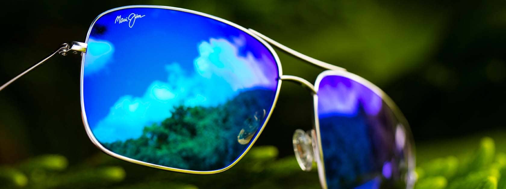 silver frame aviator sunglasses with blue lenses reflecting trees and the sky
