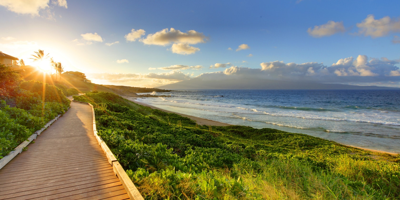 mirando el paseo que transcurre paralelo a la playa del océano mientras se pone el sol