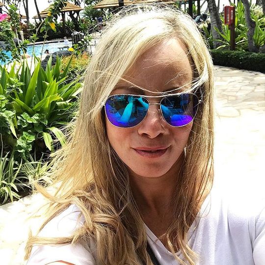 Blonde Frau mit Sonnenbrille mit blauen Gläsern, die in ihrer Ausfahrt ein Selfie macht